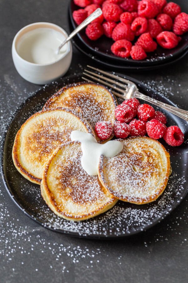 Oladi avec des baies et de la crème sure sur une assiette