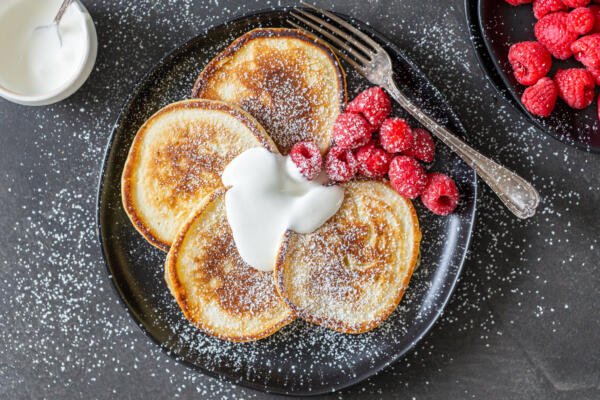 Oladi avec des baies et de la crème sure sur une assiette