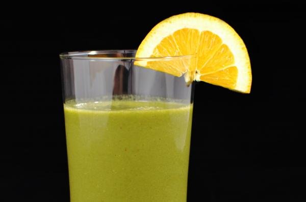 Smoothie vert avec une tranche d'orange sur le bord du verre