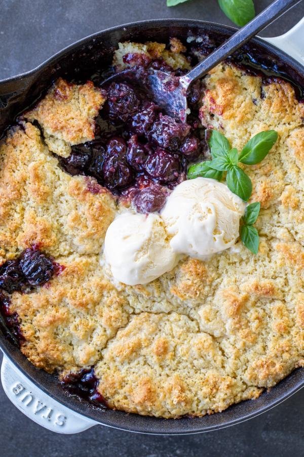 Tarte aux cerises garnie de crème glacée et d'une cuillère.