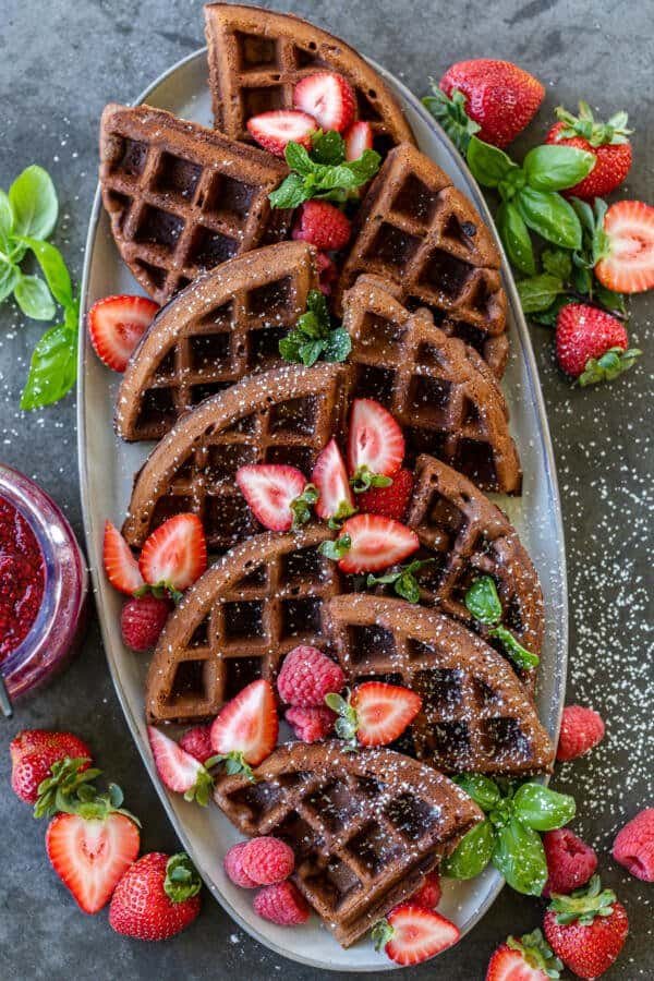 Des morceaux de gaufres chocolatées sur une assiette avec des fruits rouges