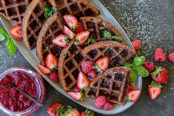 Des morceaux de gaufres chocolatées sur une assiette avec des fruits rouges