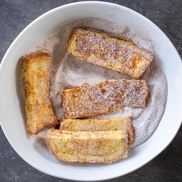 Bâtonnets de pain perdu dans un bol avec du sucre.