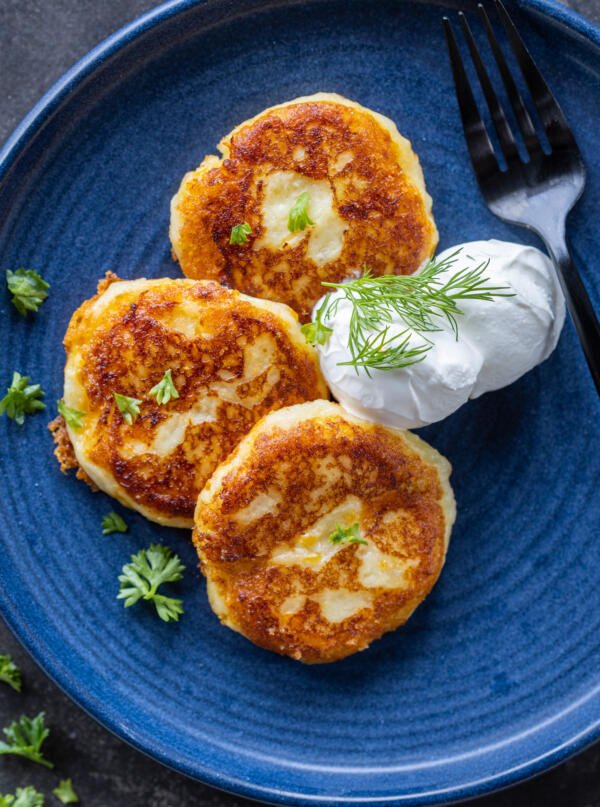 Galettes de pommes de terre écrasées sur une assiette avec une sauce aux herbes.