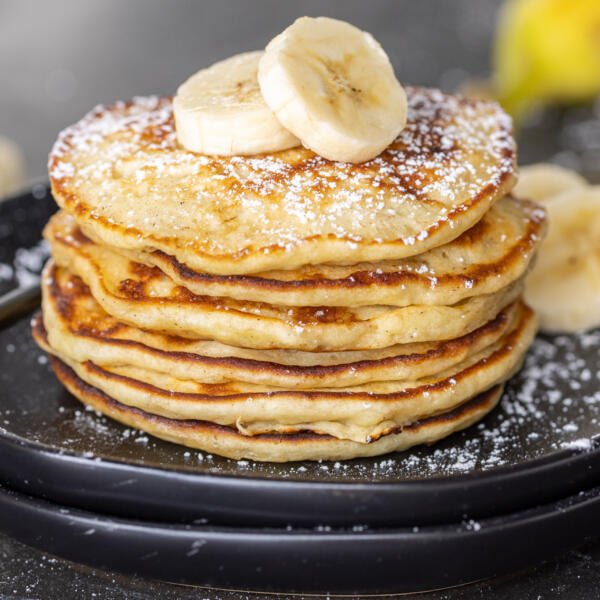 Une pile de crêpes à la banane avec des tranches de bananes dessus.