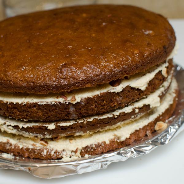 Couches de gâteau éponge avec crème et morceaux de noisettes entre chaque couche.
