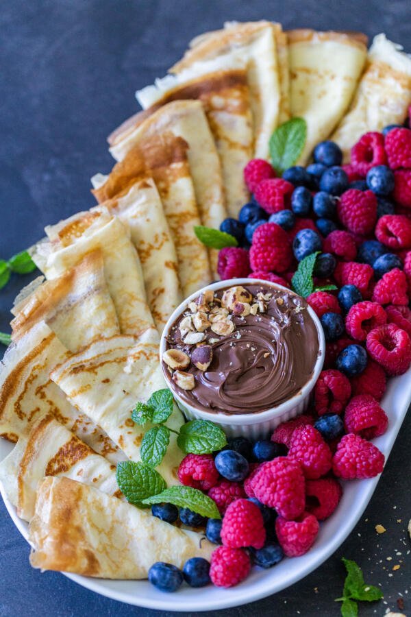 Crêpes sur un plateau avec des fruits et du Nutella