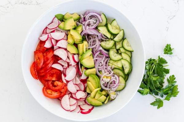 Salade dans un bol, tomates, radis, avocat, oignon et concombre
