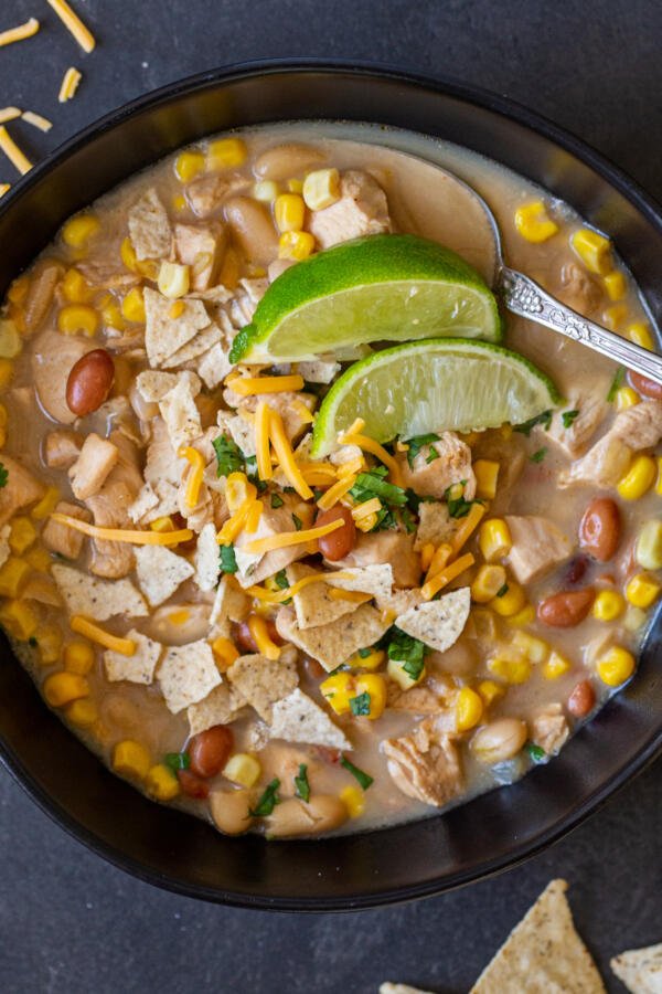 Chili au poulet blanc dans un bol avec du citron vert et des chips