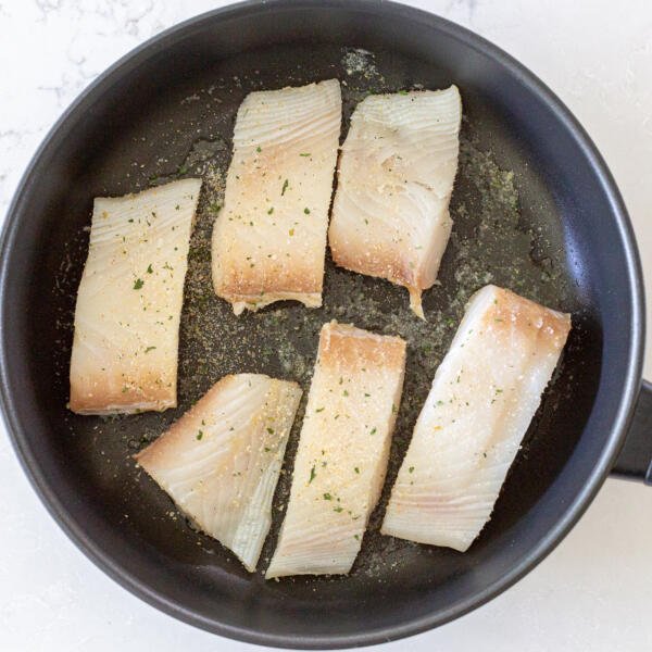 halibut en train de cuire dans une poêle.